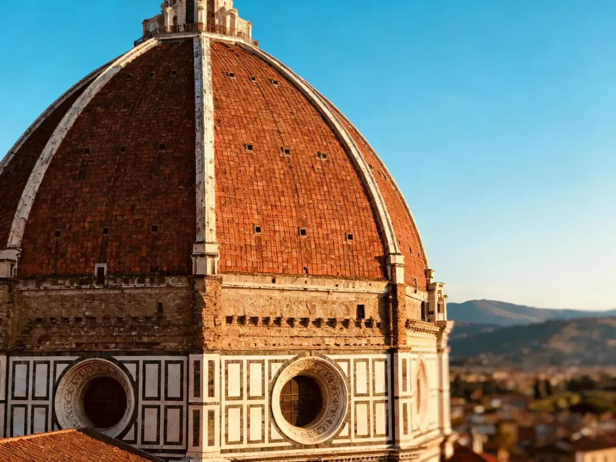 Majestatyczna, czerwona kopuła katedry Santa Maria del Fiore we Florencji na tle błękitnego nieba.